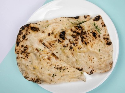 Naan bread resting on a wooden chopping board
